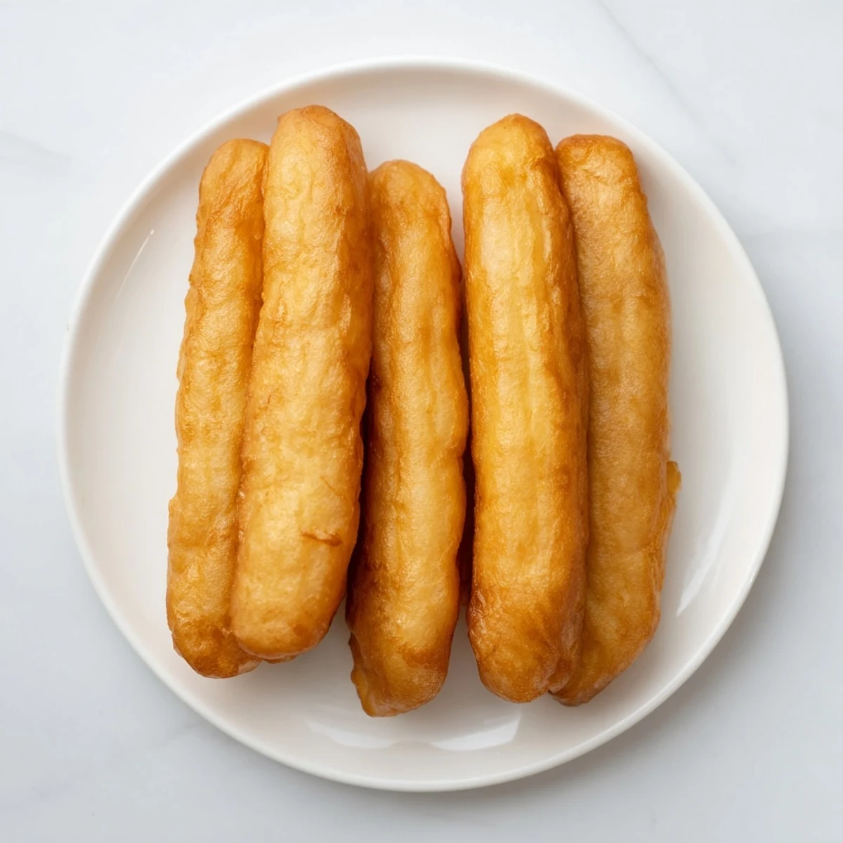 Golden fried Youtiao Chinese doughnuts piled high on a serving plate