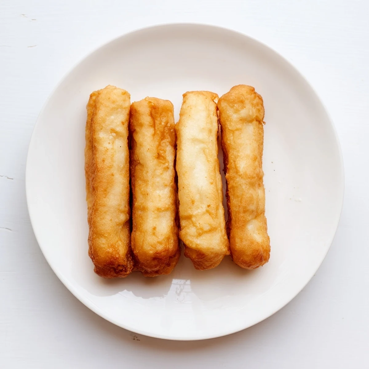 Hand-stretched Youtiao breakfast fritters frying until perfectly puffed and golden brown