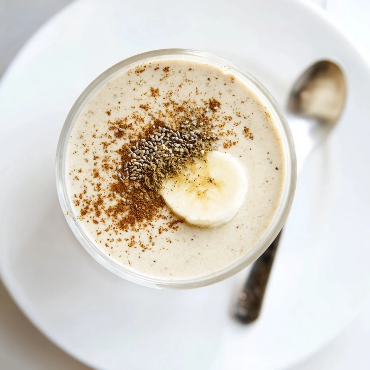 Creamy Greek yogurt banana smoothie poured into a tall glass with a straw