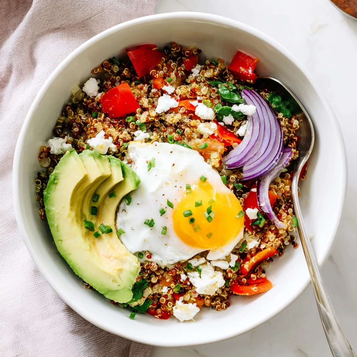 Protein-rich savory quinoa breakfast bowl featuring fried egg, wilted spinach, and vibrant cherry tomatoes