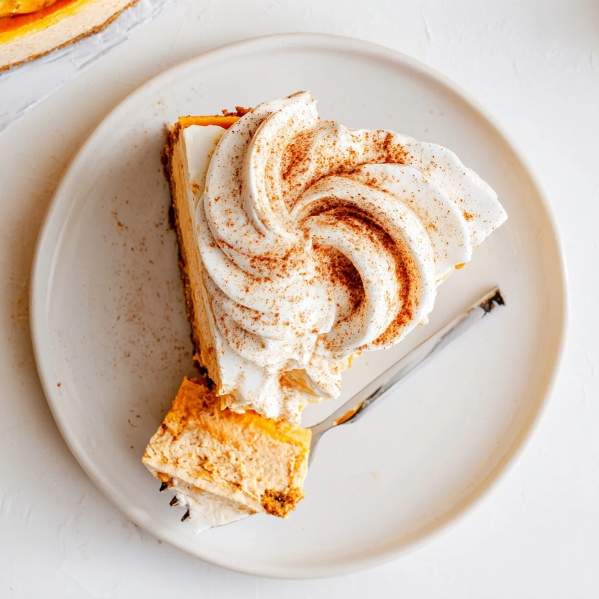 Creamy pumpkin spice Christmas cheesecake with graham cracker crust topped with dollop of sweetened whipped cream