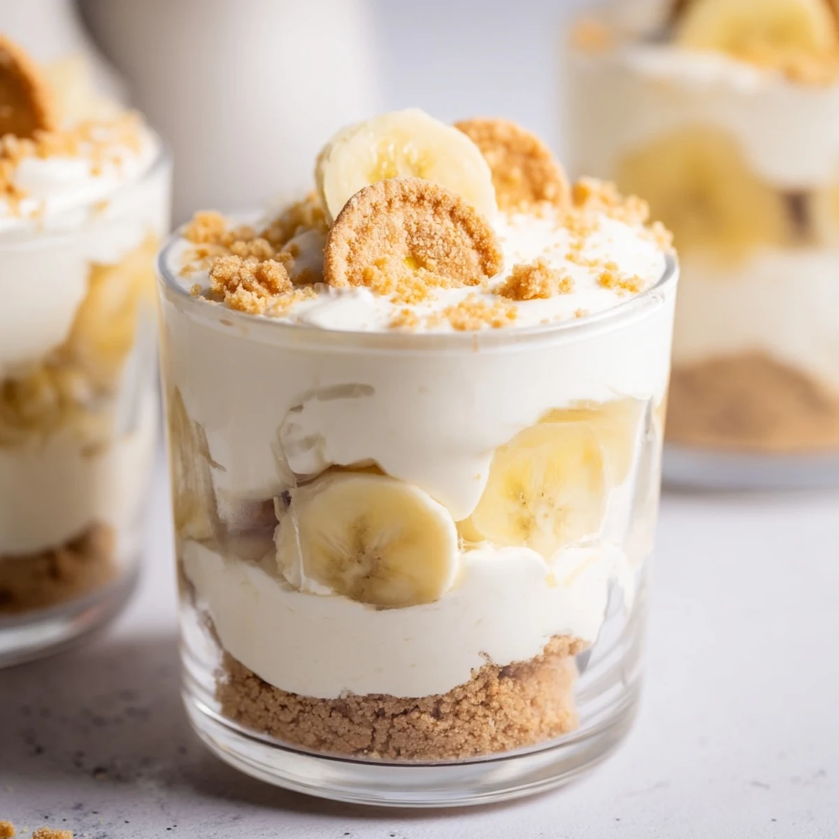 Creamy no bake banana pudding cheesecake cups layered with fresh banana slices and vanilla wafer crumbs