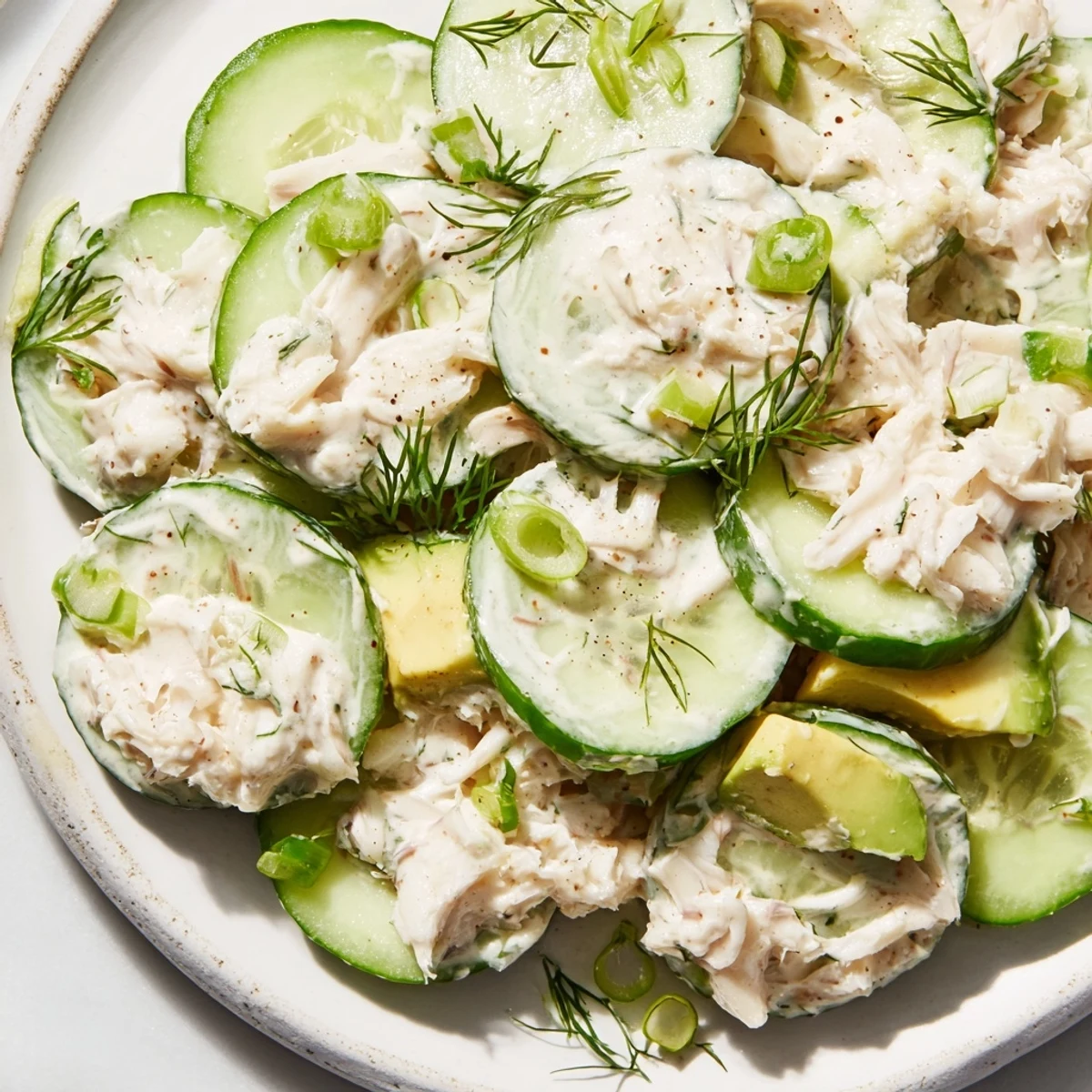 Crisp cucumber salad with crab meat tossed in creamy dressing, garnished with fresh dill