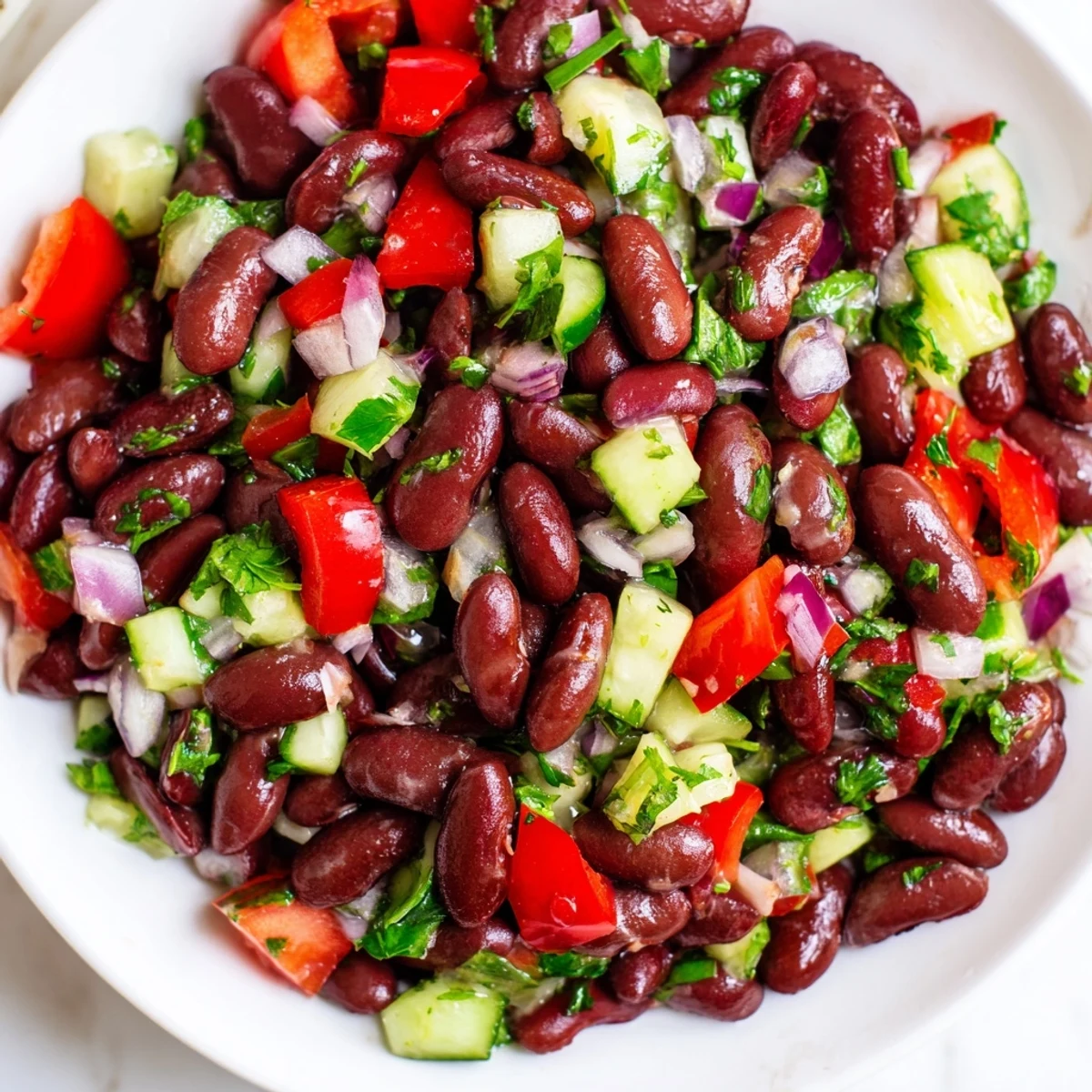 Creamy kidney bean salad topped with fresh parsley and diced red bell peppers