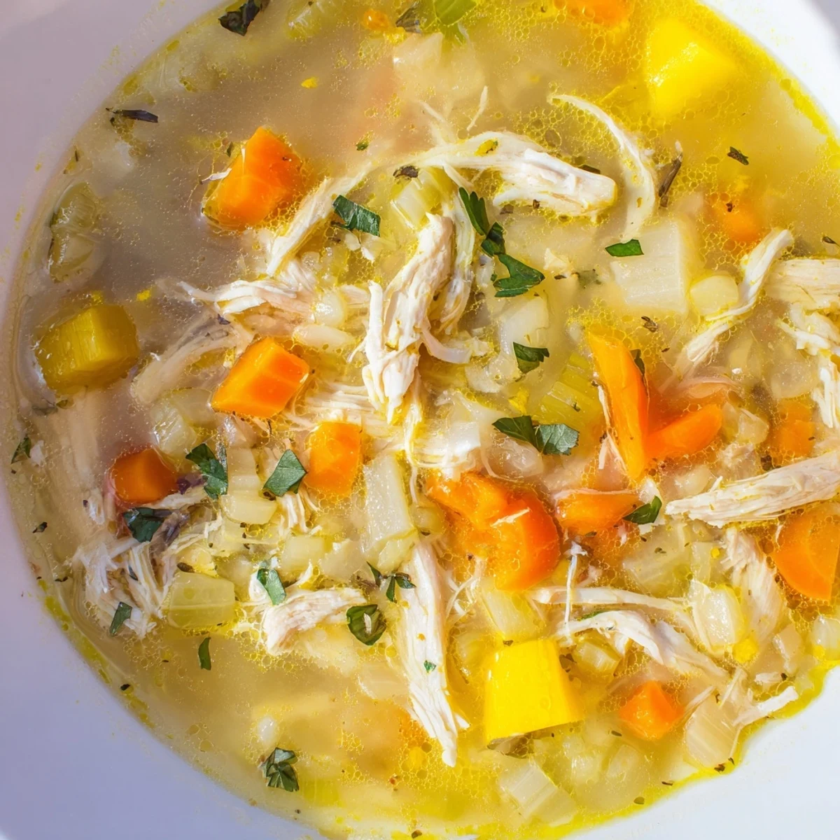 Golden crockpot lemon chicken soup with tender shredded meat and bright citrus flavor
