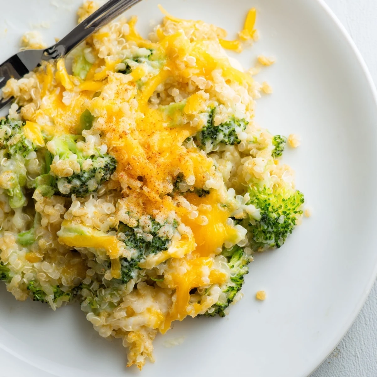 A cozy bowl of creamy broccoli quinoa casserole garnished with fluffy quinoa and tender broccoli florets