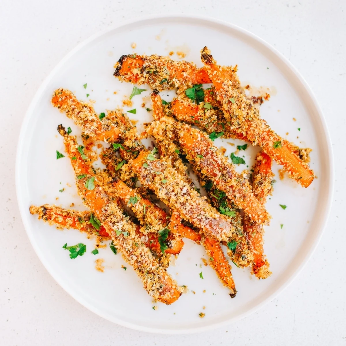 Tender Parmesan crusted carrots with golden brown edges served on white plate with parsley garnish