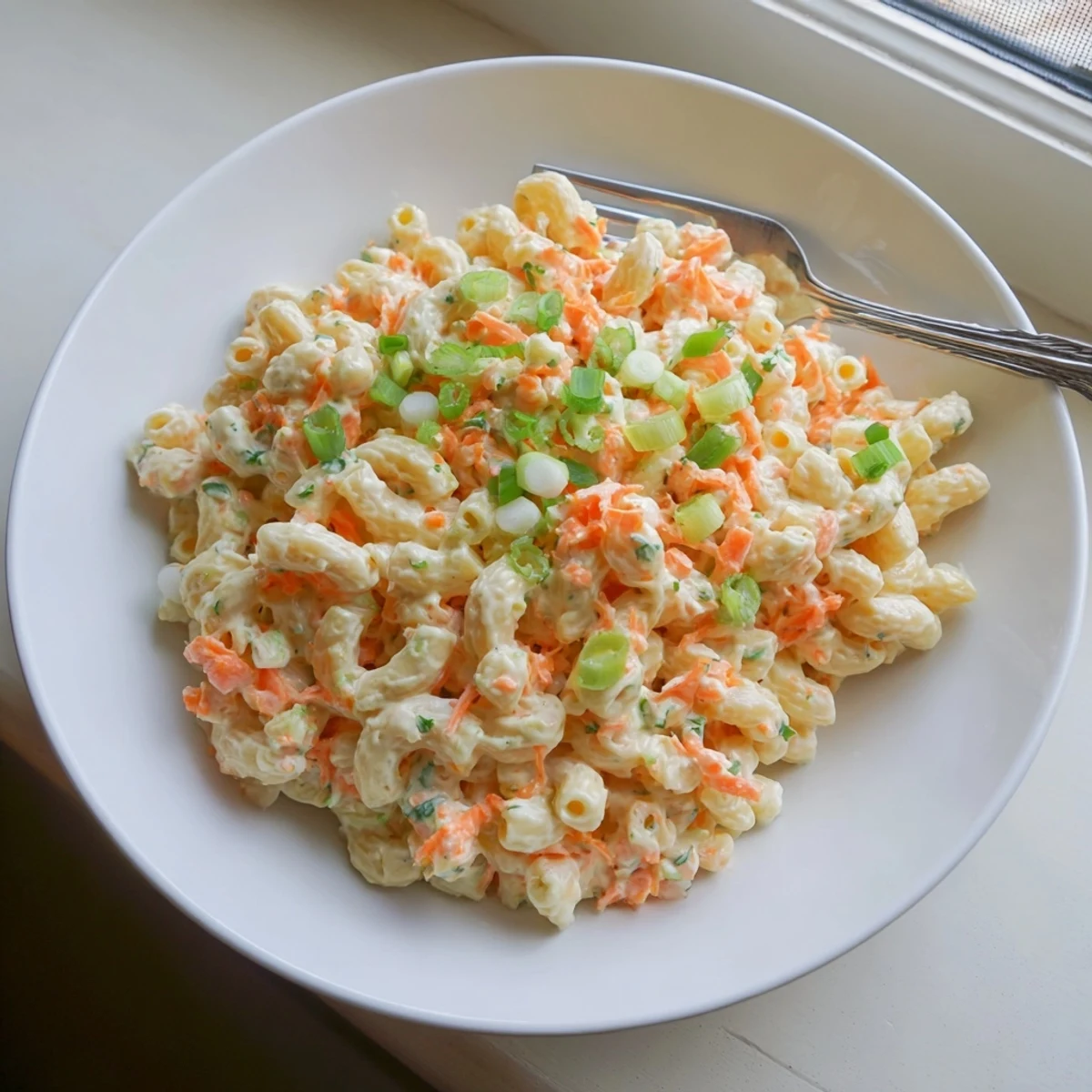Scoop of smooth Hawaiian style mac salad served alongside traditional plate lunch featuring overcooked pasta and creamy vinegar dressing