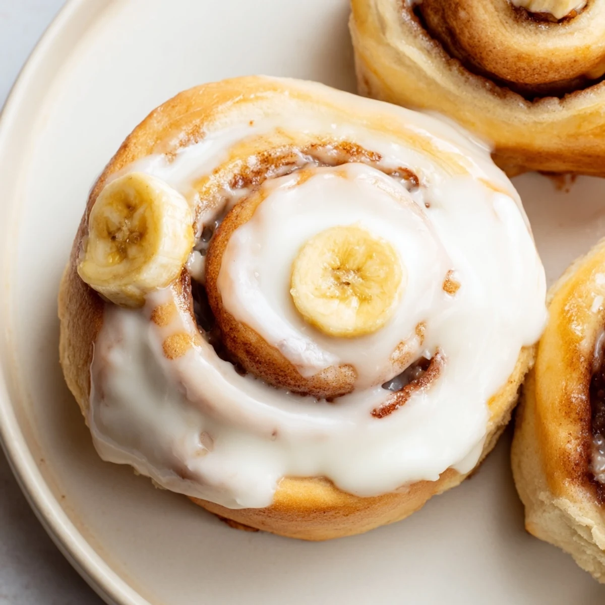 Freshly baked banana cinnamon rolls swirled with cinnamon and dripping with sweet cream cheese frosting
