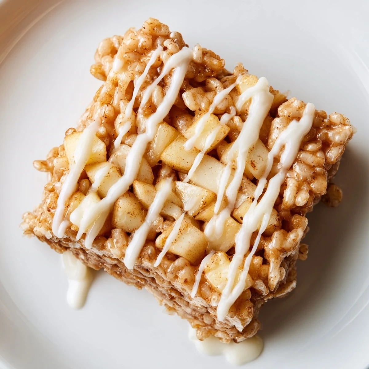 Golden apple pie rice krispie treats drizzled with white chocolate on a white plate