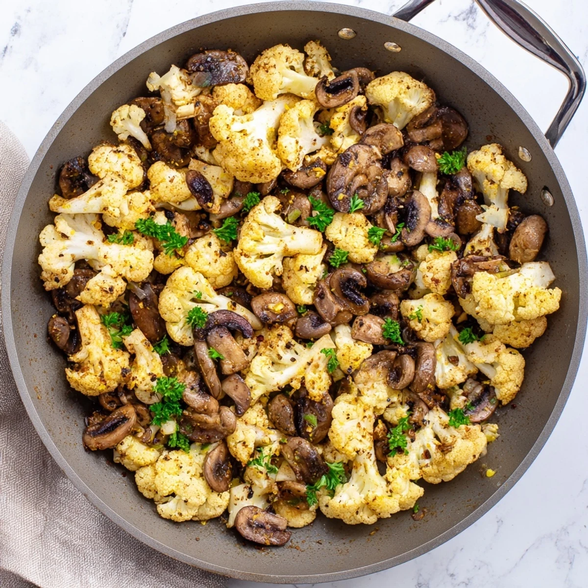 Vegetarian garlic mushrooms and cauliflower skillet topped with parsley in a cast iron pan
