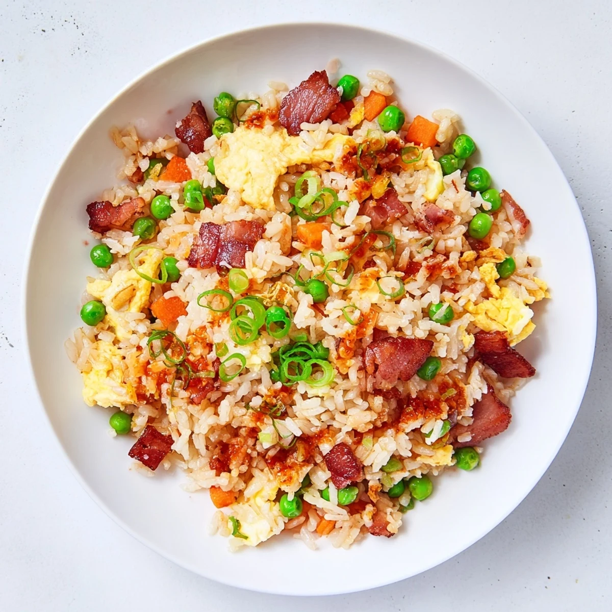 Heaping plate of Asian fusion breakfast fried rice topped with green onions and optional sriracha drizzle