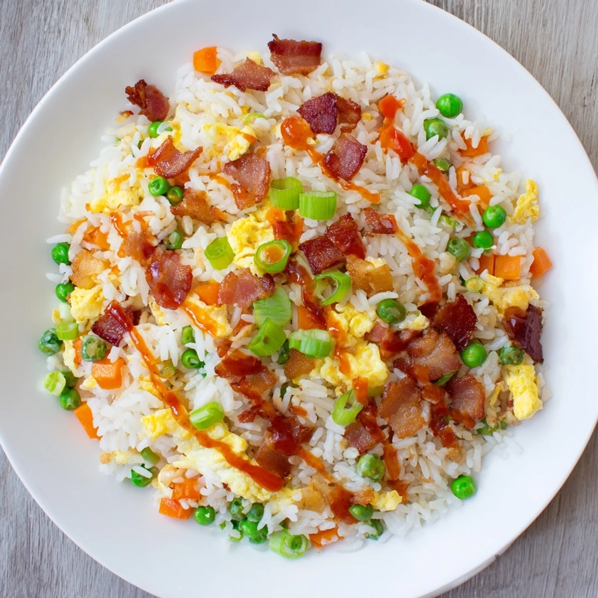 Golden breakfast fried rice with crispy bacon scrambled eggs and colorful peas in a skillet
