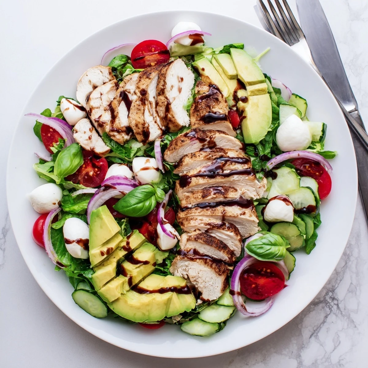 Colorful baked marinated chicken salad with fresh mozzarella and balsamic vinaigrette drizzled over mixed greens