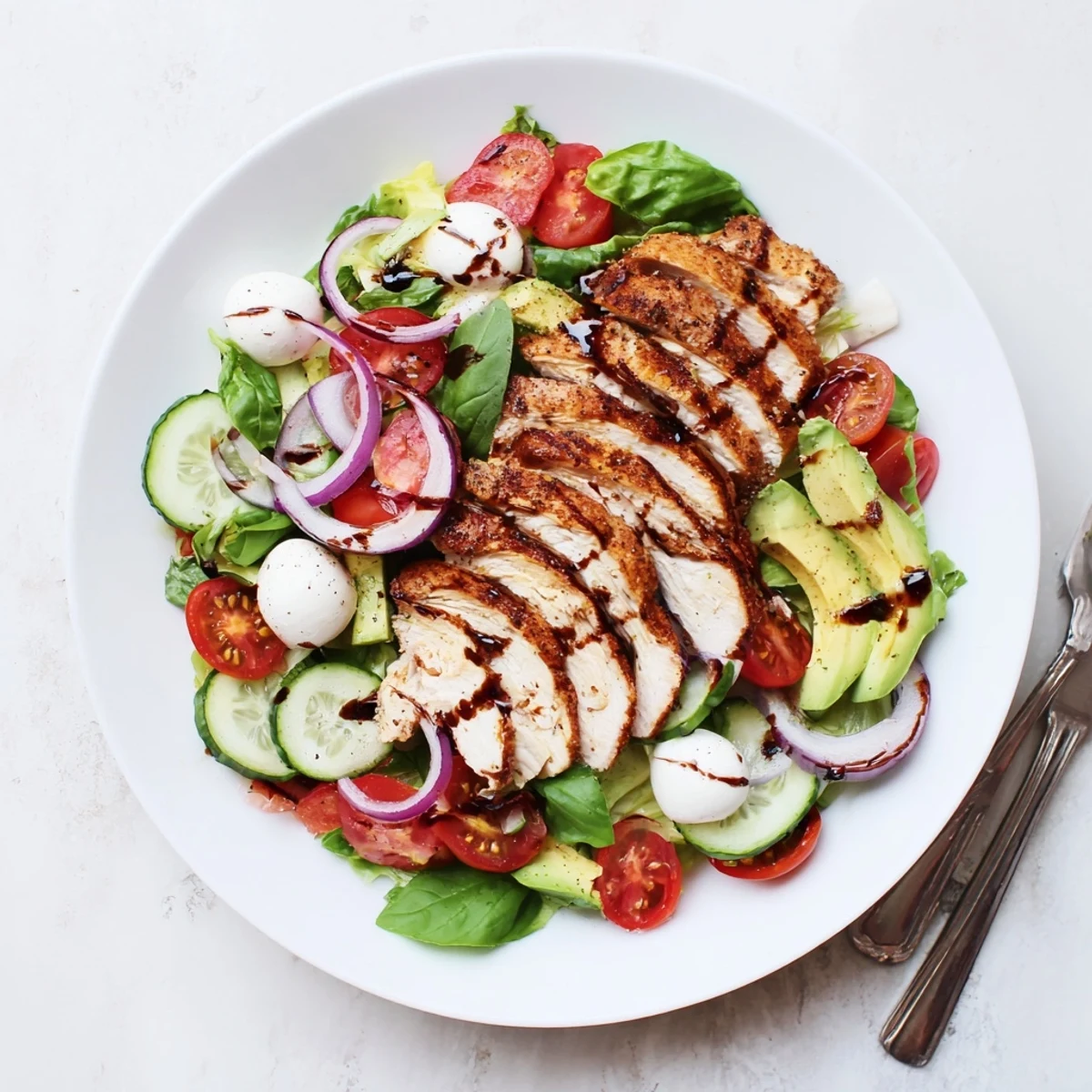 Tender sliced baked chicken atop crisp salad greens with cherry tomatoes and creamy mozzarella balls