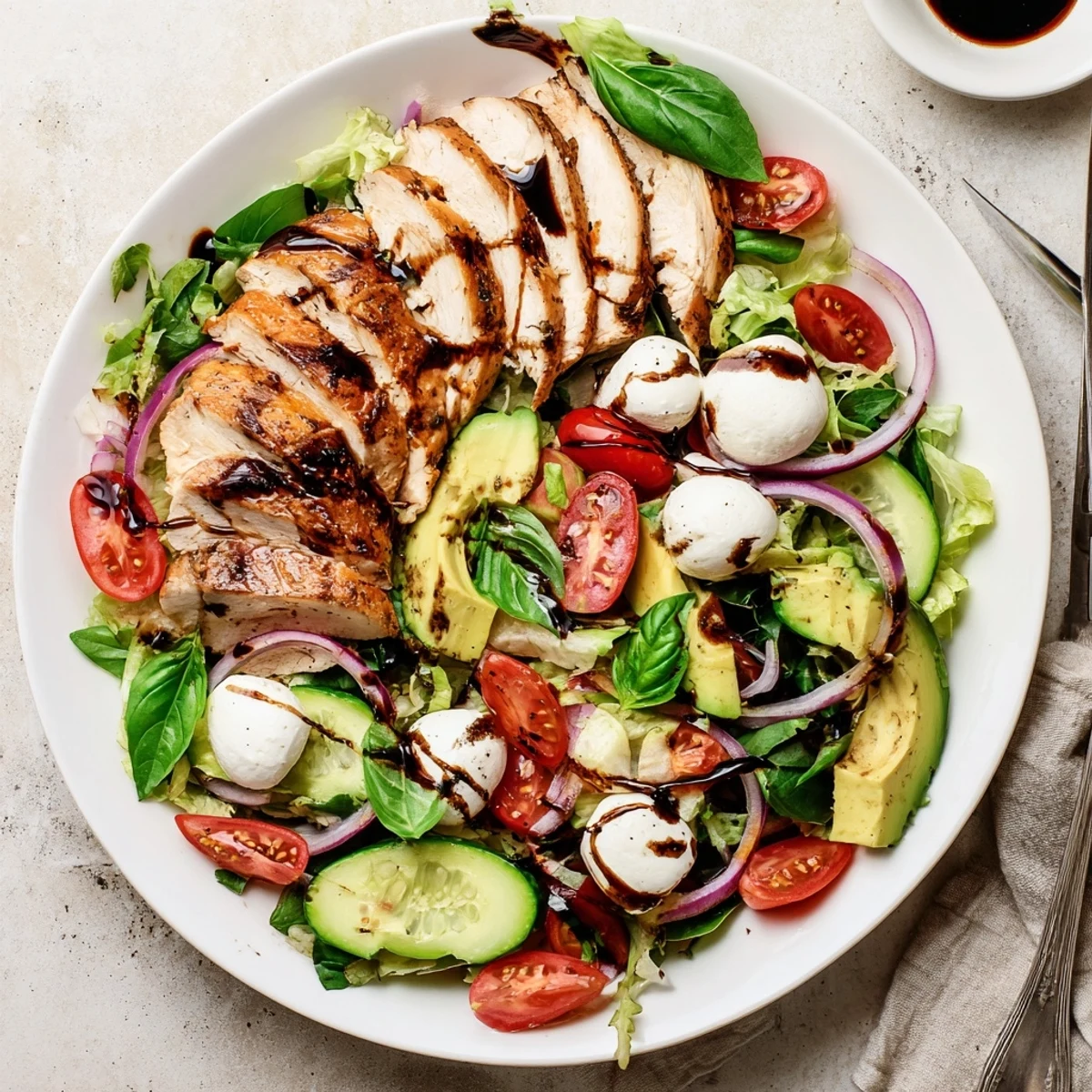 Gluten-free main dish salad featuring marinated baked chicken, fresh vegetables, and tangy balsamic dressing