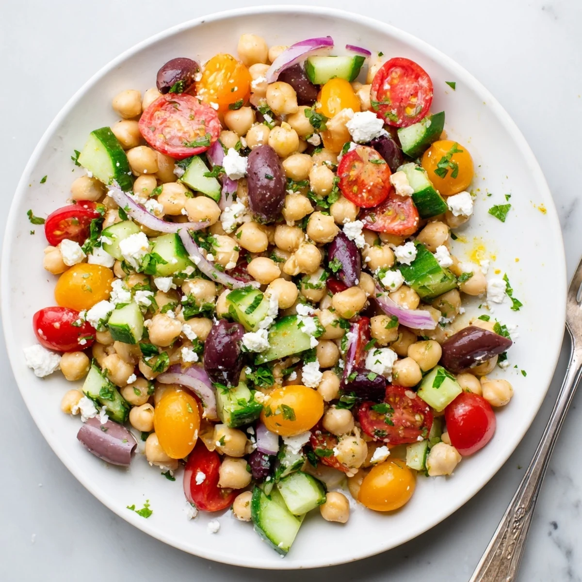 Colorful Mediterranean chickpea salad bowl topped with fresh parsley and crumbled feta cheese