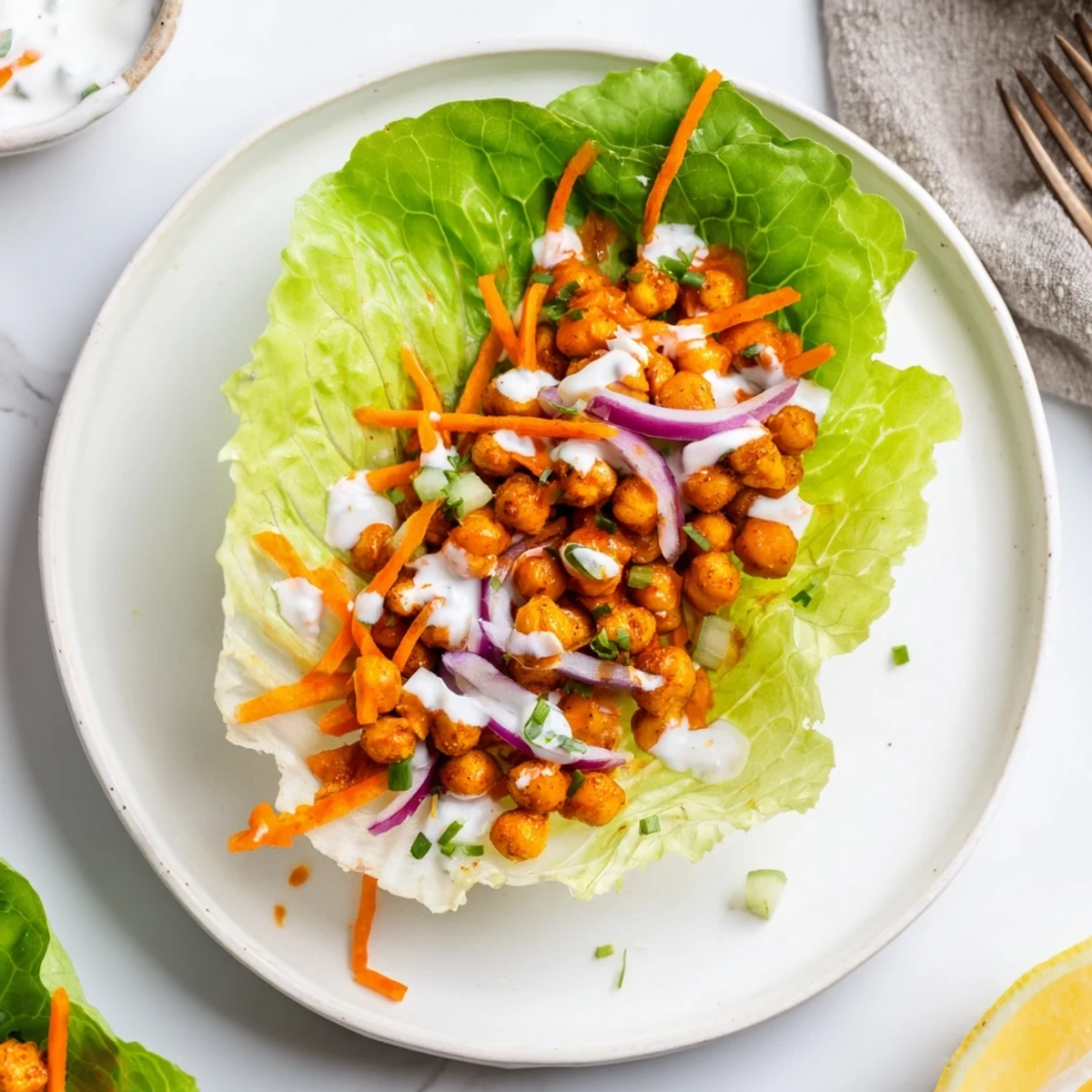Buffalo Chickpea Lettuce Wraps piled on platter, spicy chickpeas glistening  