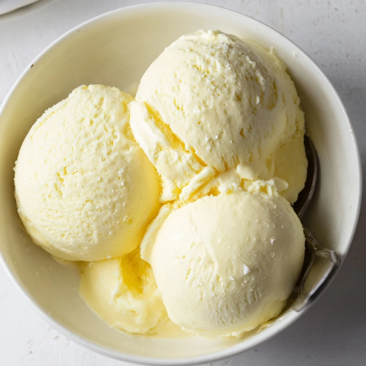 Creamy homemade vanilla ice cream scooped into a chilled glass dessert bowl with fresh berries
