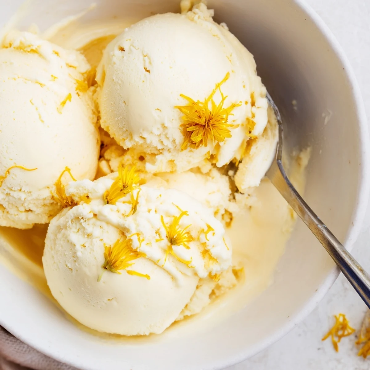 Creamy dandelion honey ice cream scooped into vintage bowls garnished with fresh edible flowers