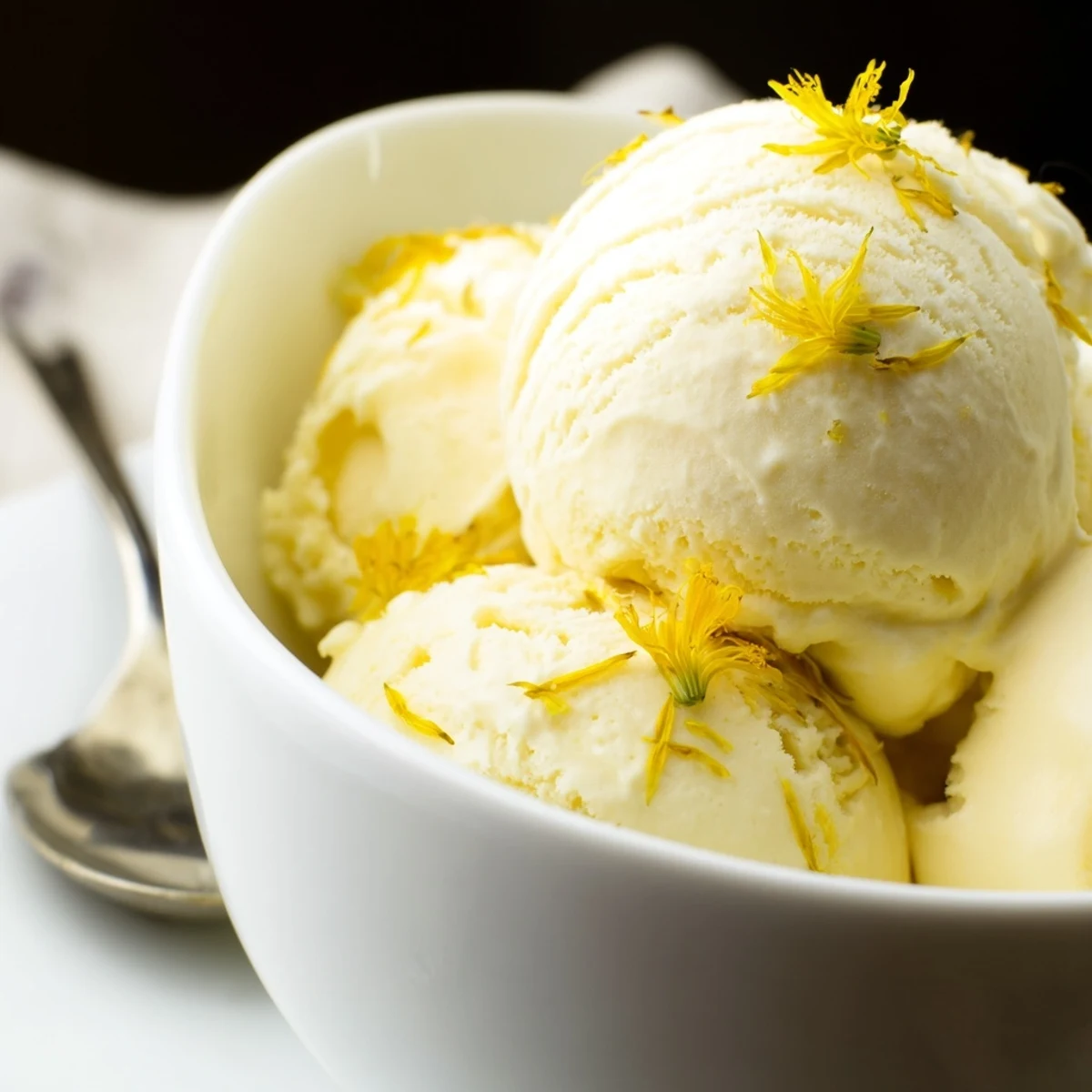 Golden scoops of floral dandelion honey ice cream melting atop waffle cones on summer day