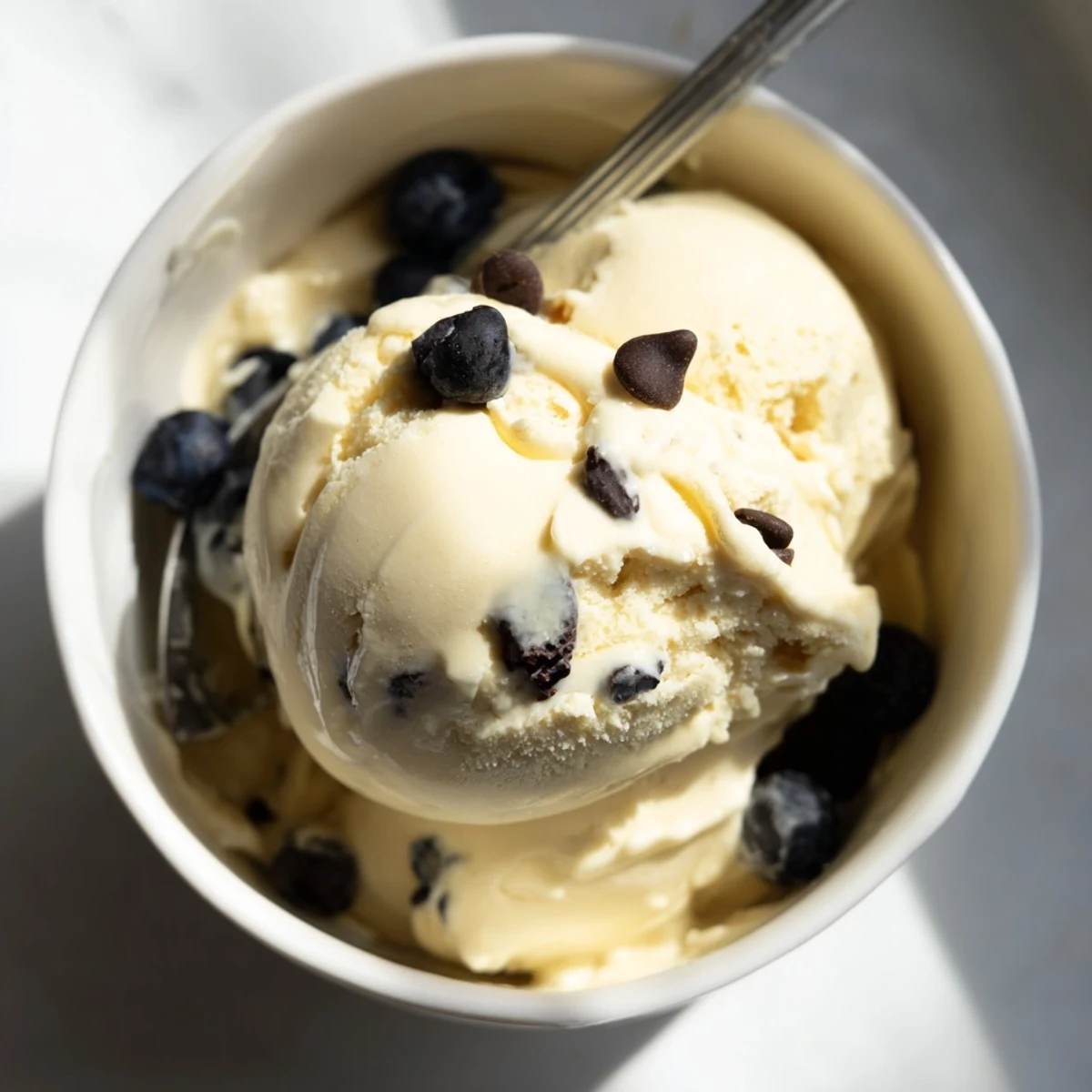 Creamy banana nice cream served in a bowl with fresh berries and chopped nuts