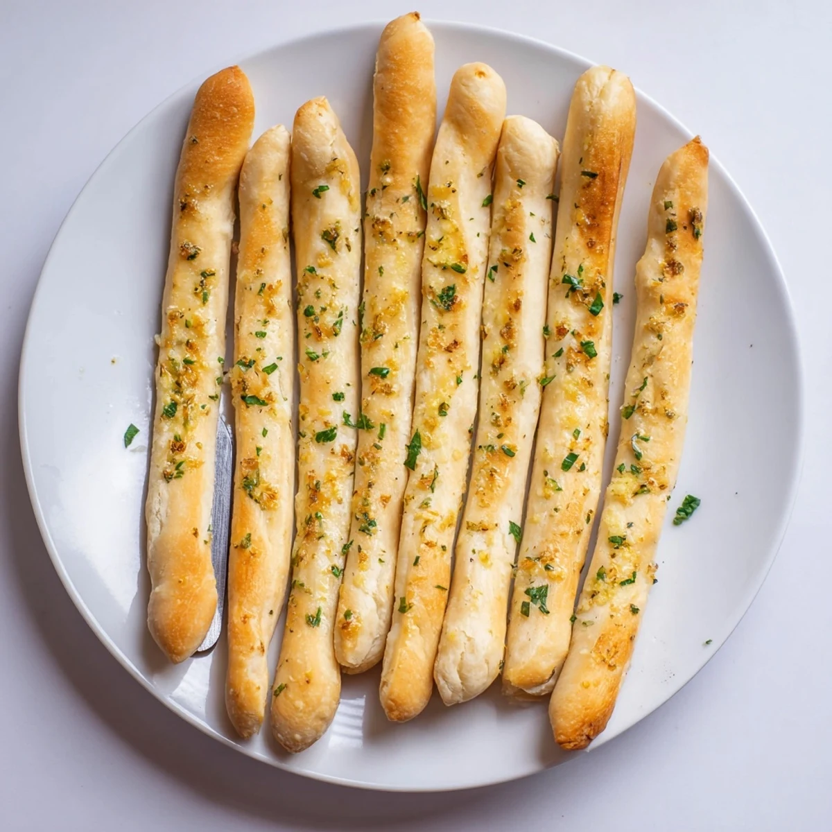 Golden homemade garlic breadsticks fresh from the oven brushed with melted butter and parsley