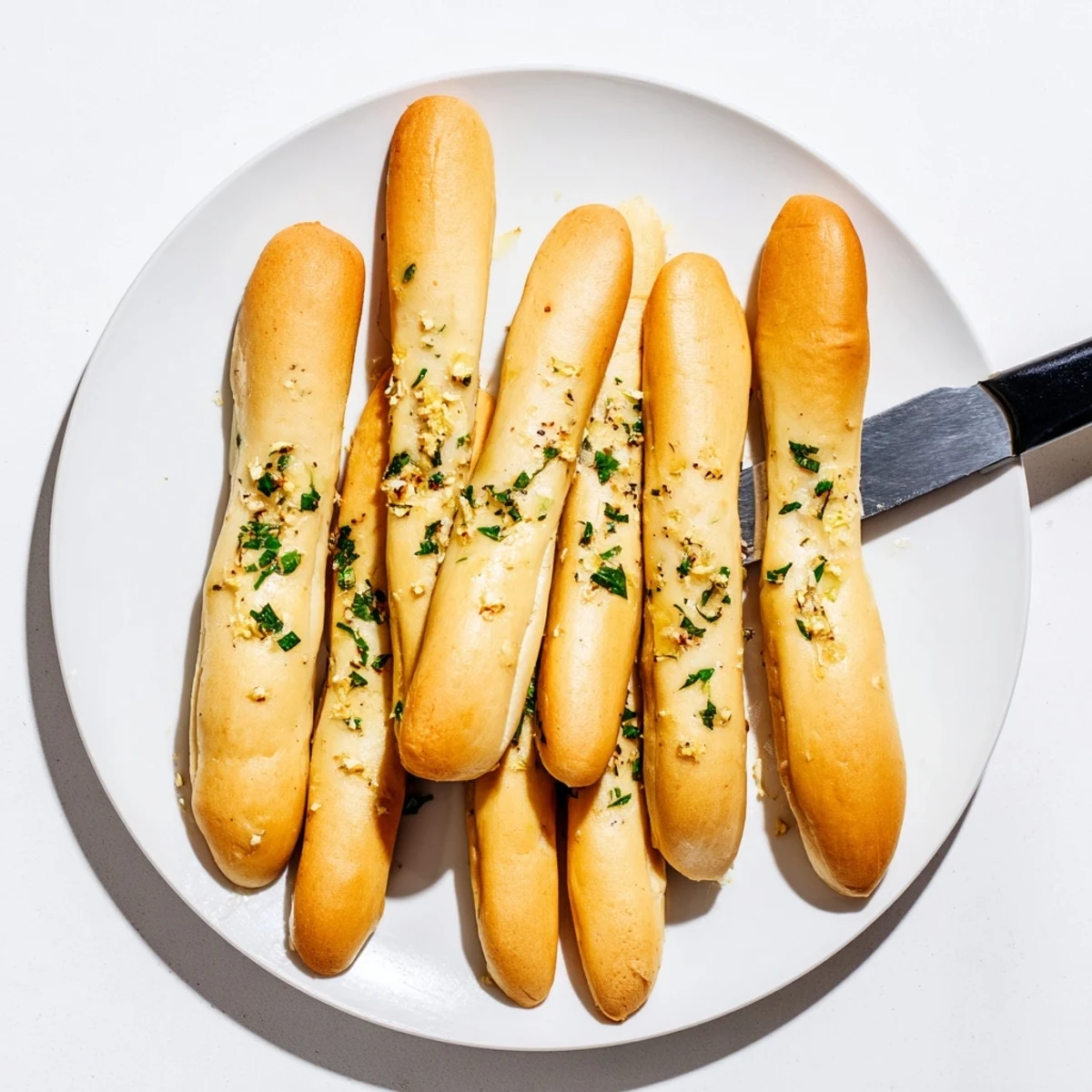 Fluffy golden breadsticks coated in garlic butter and herbs ready for sharing at dinner