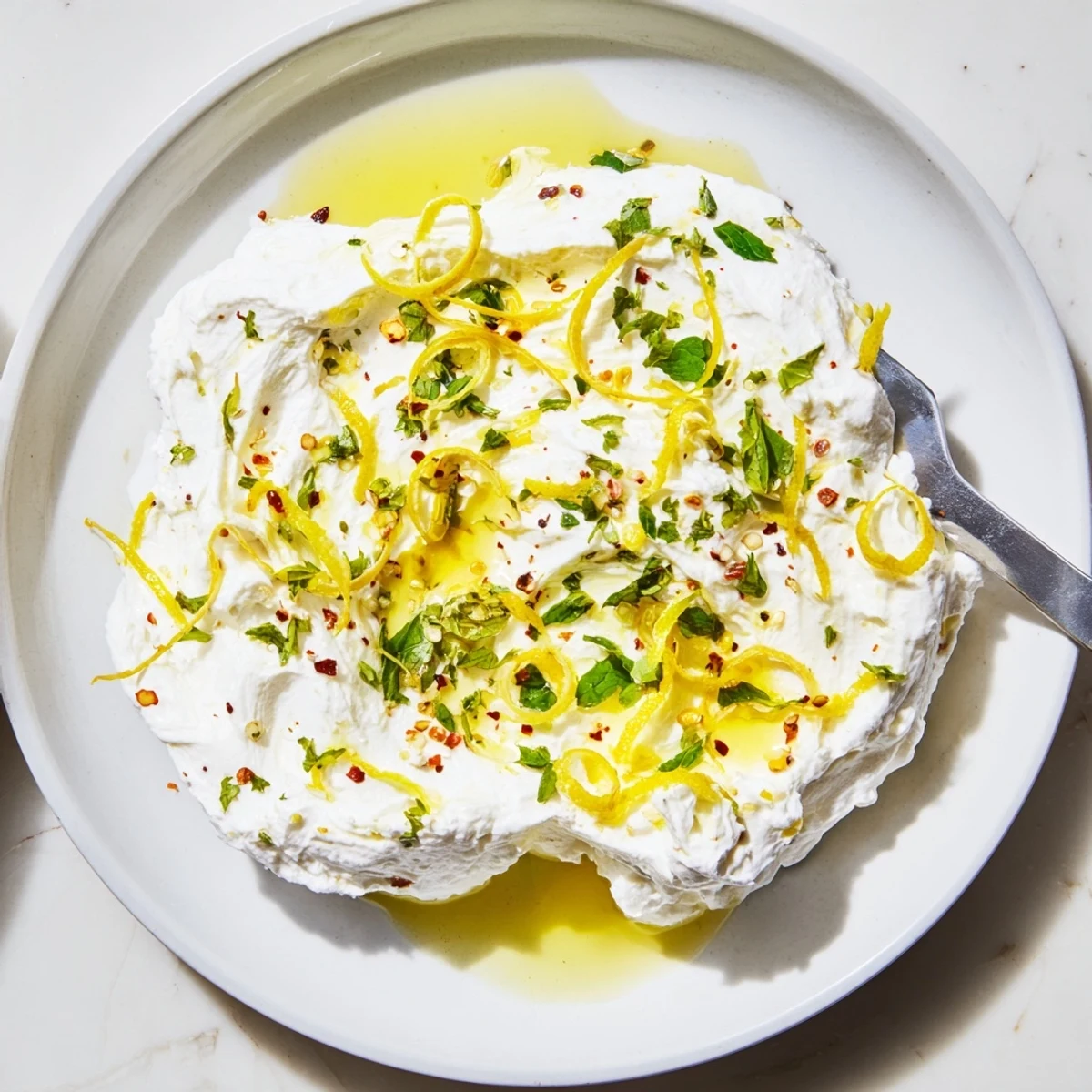 Creamy whipped ricotta topped with fresh herbs and lemon zest served on rustic wooden board