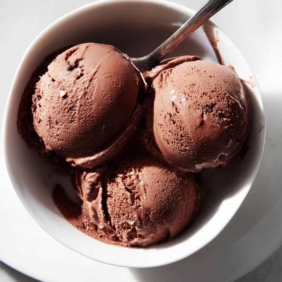 Creamy chocolate sourdough ice cream scooped into a vintage glass bowl with dark chocolate shavings on top