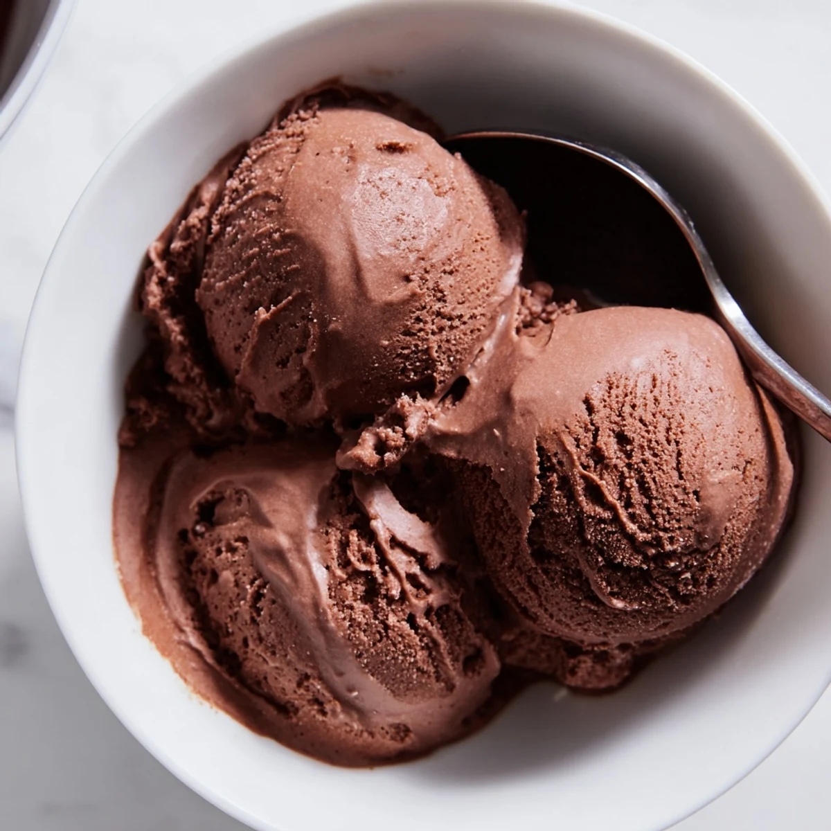 Homemade chocolate sourdough ice cream garnished with fresh raspberries and a drizzle of chocolate sauce