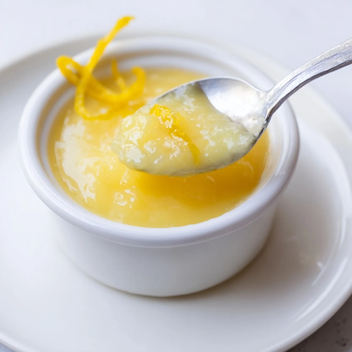 Smooth Homemade Lemon Curd spooned over warm scones, bright citrus aroma