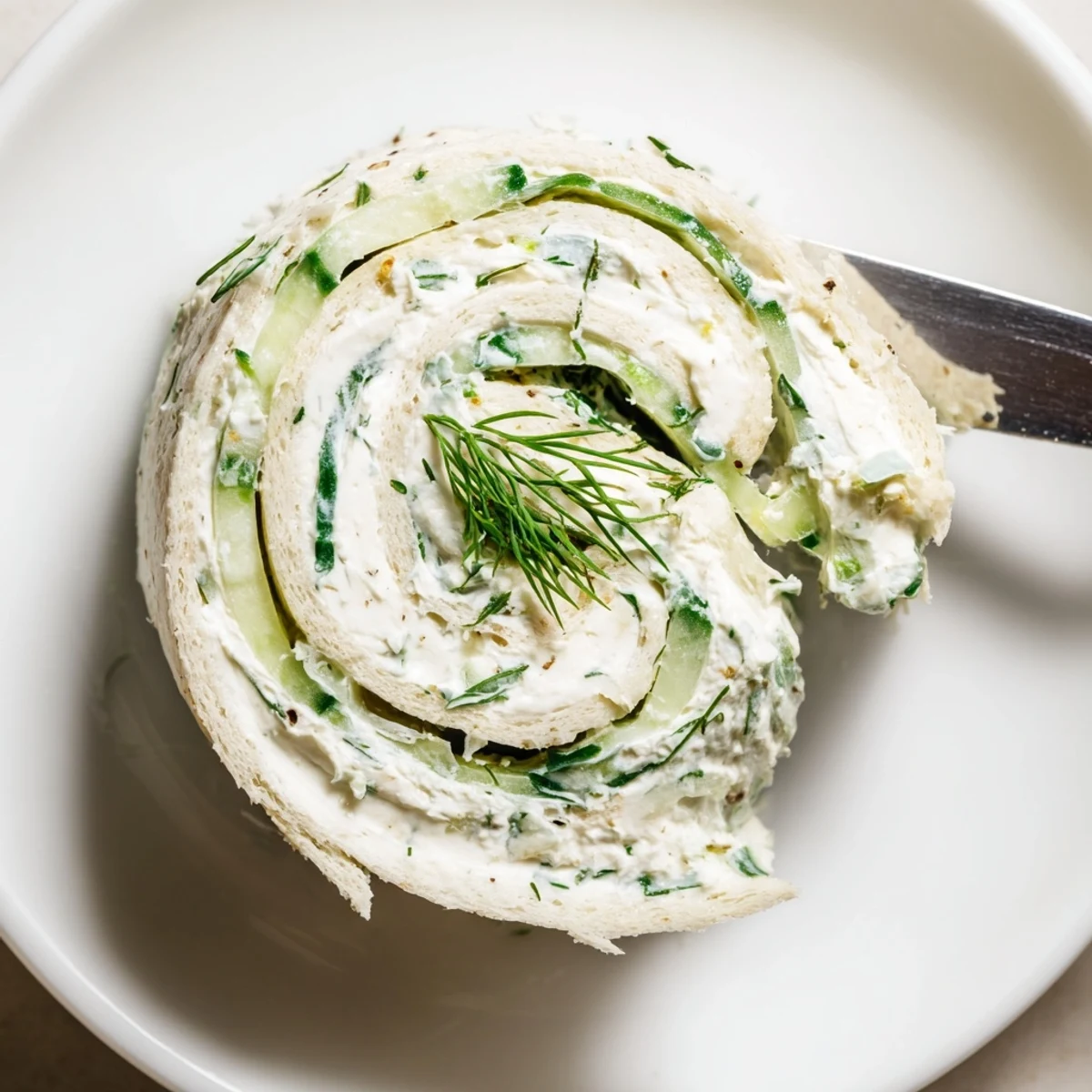 Cucumber And Dill Pinwheels arranged on platter, creamy filling and fresh herbs
