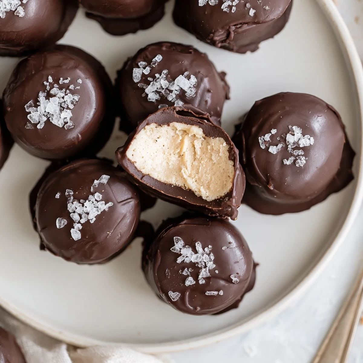 Hand-dipped Frozen Peanut Butter Greek Yogurt Bites cooling on sheet, glossy chocolate finish