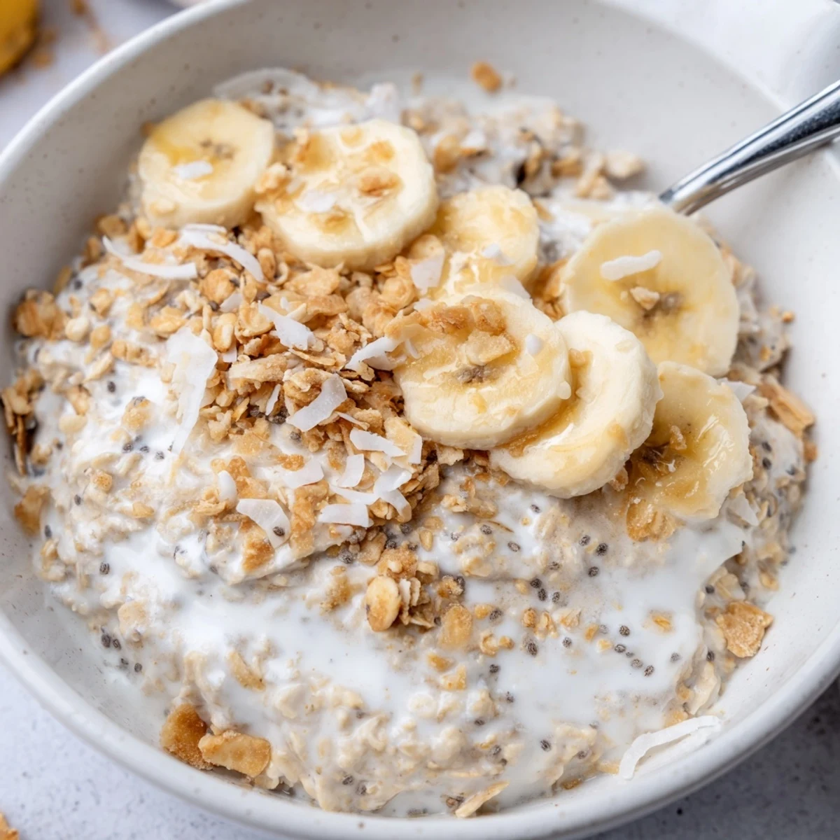 Coconut Cream Pie Overnight Oats with toasted coconut, creamy texture, banana slices  