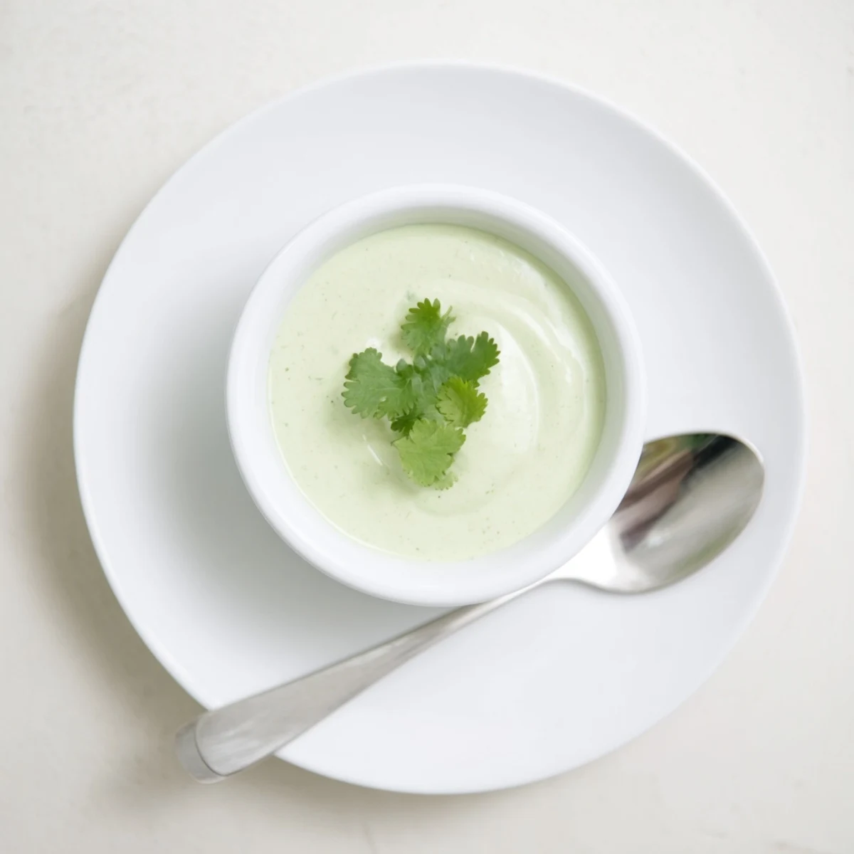 Vibrant green cilantro lime dipping sauce in small ramekin surrounded by tortilla chips