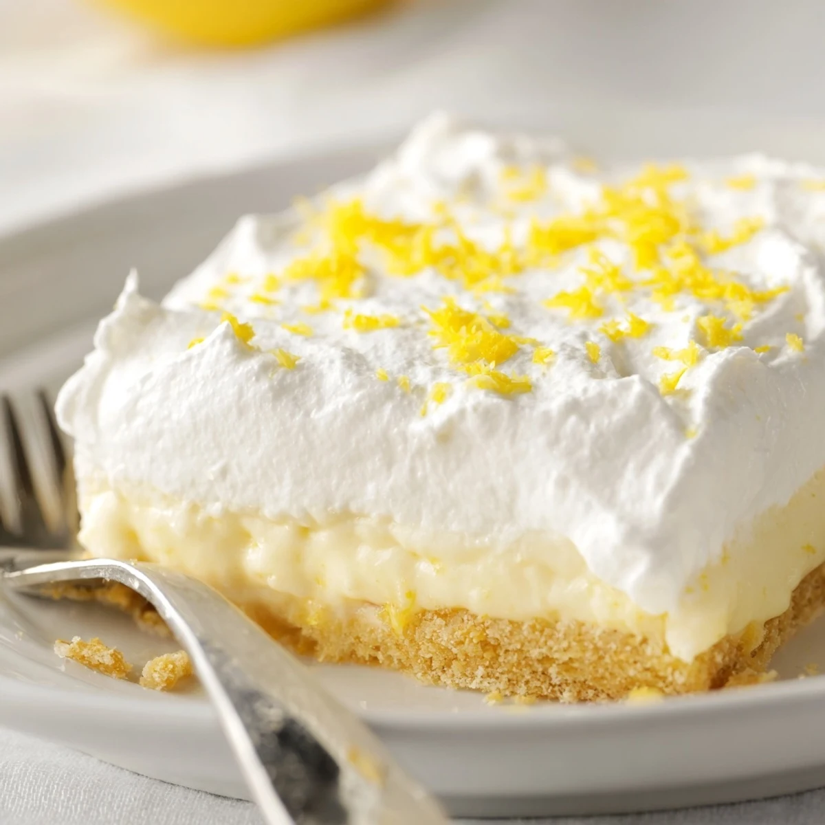 Homemade Lemon Lush Cake featuring buttery crust, tangy lemon pudding, and fluffy whipped cream layers
