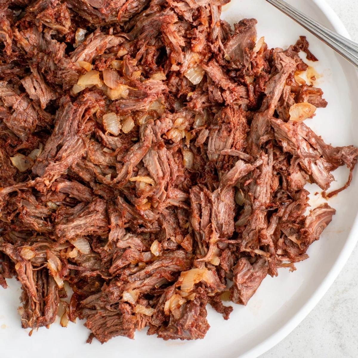 Savory Mexican slow cooker beef barbacoa with rich chipotle sauce draped over perfectly tender shredded meat
