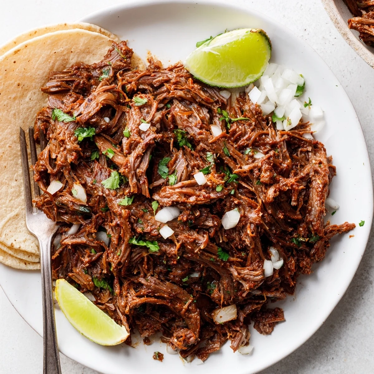 Family-style Slow Cooker Beef Barbacoa, tender smoky meat garnished with lime