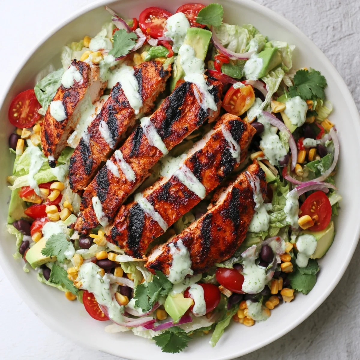 Bowl of Southwestern Chicken Salad topped with charred chicken and zesty dressing.