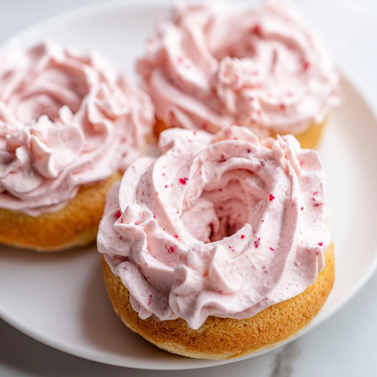 Fresh Strawberry Buttercream Frosted Donuts arranged on a pastel plate for a sweet brunch