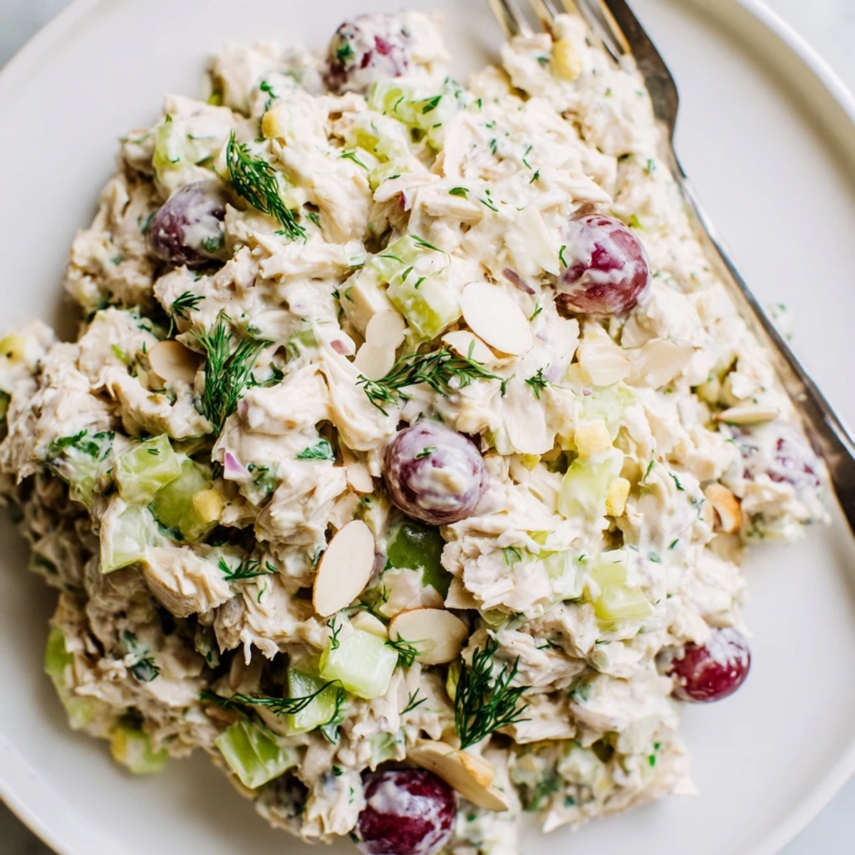 Creamy vegan chicken salad piled high on toasted whole grain bread with fresh herbs