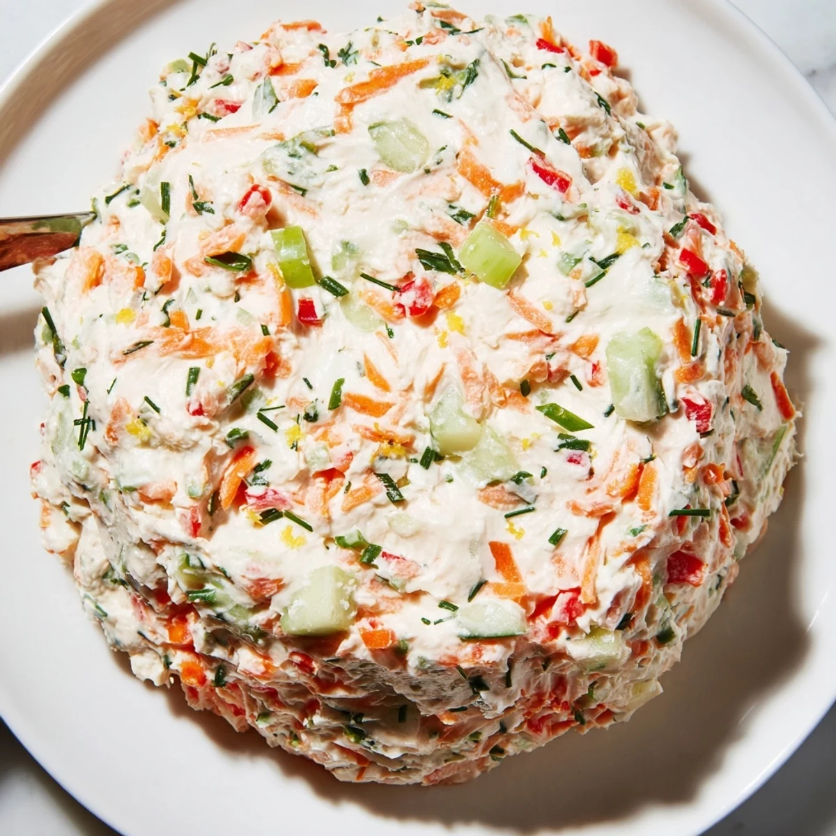 Vibrant garden vegetable spread in a bowl surrounded by toast points and fresh herbs