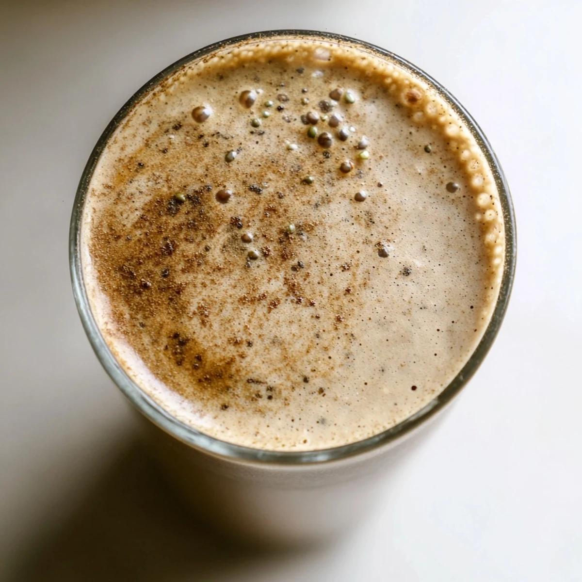 Thick banana protein coffee smoothie poured into a mason jar beside fresh ripe bananas