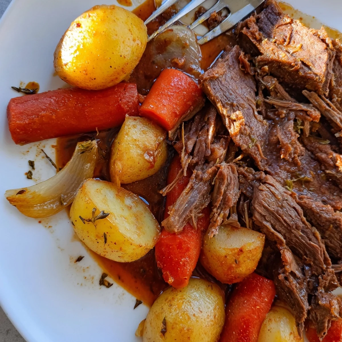 Tender perfect pot roast surrounded by carrots and potatoes in rich broth