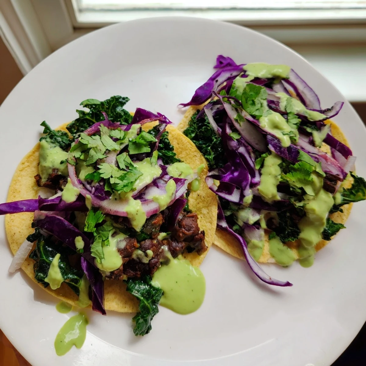 Crispy corn tortillas loaded with smoky black beans sautéed kale and rich avocado green sauce