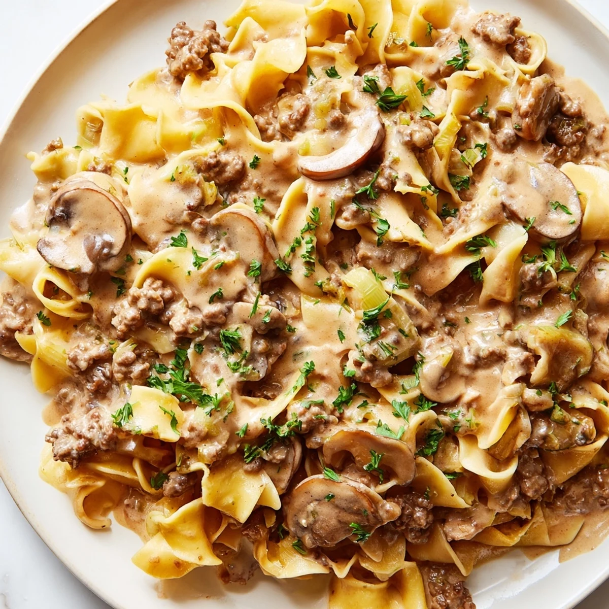 Creamy hamburger stroganoff served over tender egg noodles with fresh parsley garnish