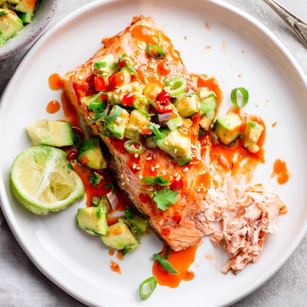 Crispy baked Bang Bang Salmon drizzled with spicy creamy sauce and fresh avocado cucumber salsa