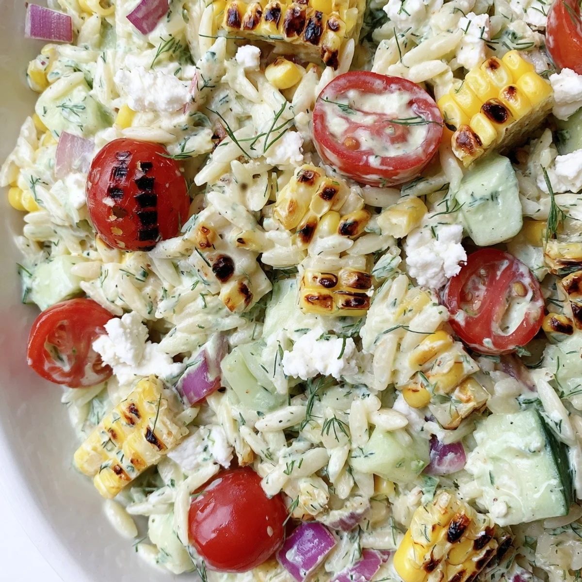 Grilled corn orzo salad served in a white bowl with juicy tomatoes and fresh dill