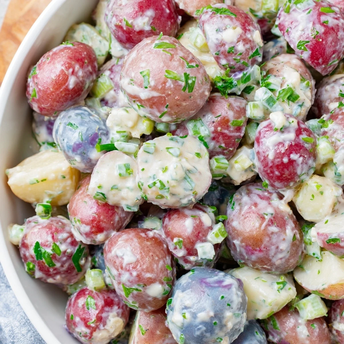 Creamy red white blue potato salad nestled in a rustic serving bowl with fresh herbs
